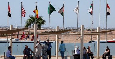 People rest in a shade near fluttering national flags at the Peace Square, ahead of an international summit on Gaza, held amid a ceasefire between Israel and Hamas, at Egypt&#039;s Red Sea resort of Sharm el-Sheikh, Egypt, Oct. 12, 2025. (Reuters Photo)