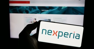 Person holding a mobile phone with the logo of semiconductor company Nexperia, Stuttgart, Germany, June 18, 2023. (Shutterstock)