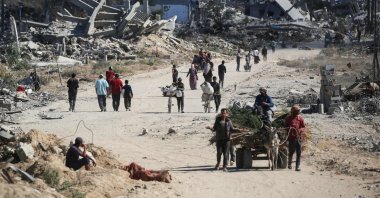Displaced Palestinians walk past destroyed buildings as they return to their homes in the al-Zahra area, central Gaza Strip, Palestine, Oct. 14, 2025. (AFP Photo)