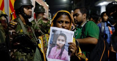 A relative mourns while holding a picture of a missing relative following a fire that broke out at a garment factory and a chemical warehouse in Dhaka, Bangladesh, Oct. 14, 2025. (Reuters Photo)