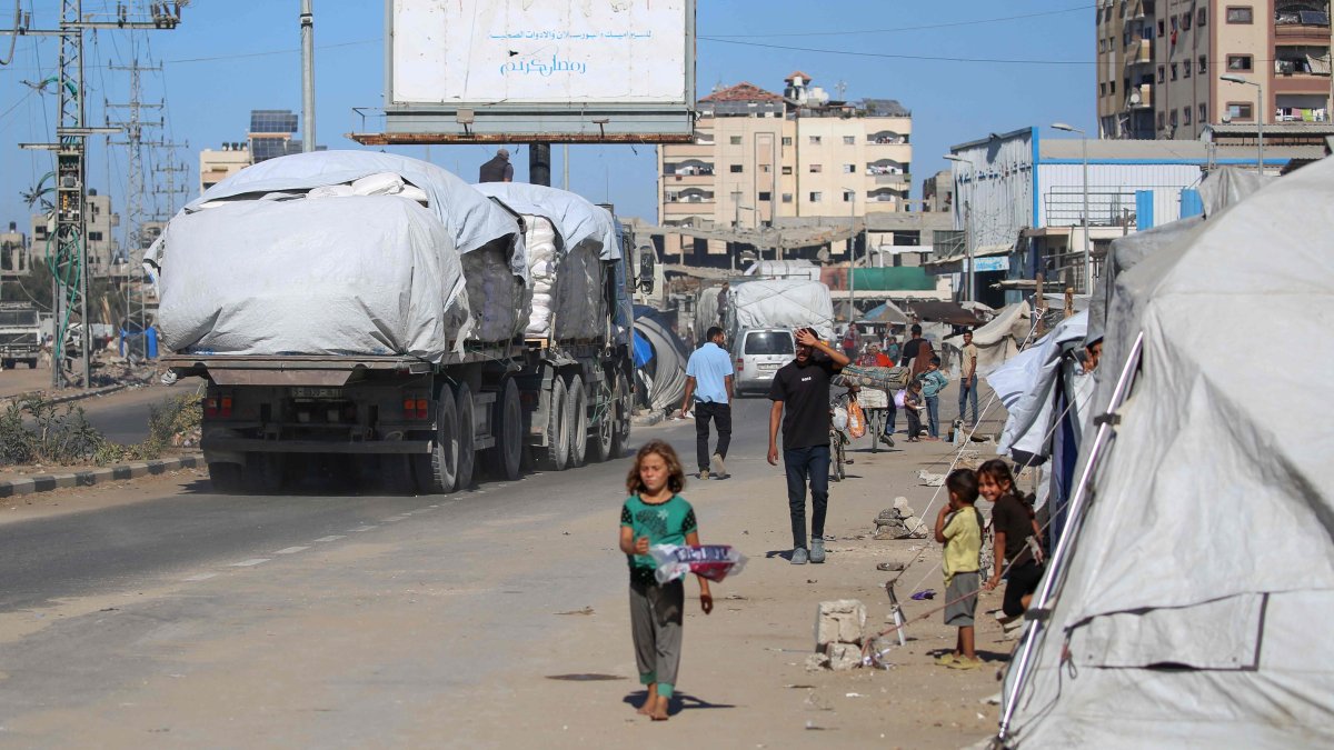 Trucks carrying aid that entered Gaza through the Karm Abu Salem crossing, drive past displacement tents at the Nuseirat refugee camp in the central Gaza Strip, Palestine, Oct. 14, 2025. (AFP Photo)