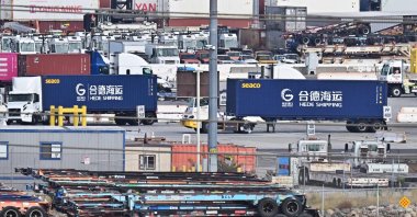 Container trucks from Hede Shipping, from the Chinese state-owned Hebei Port Group, pass a row of flatbed trailers at the Port of Los Angeles in Los Angeles, California, U.S., Oct. 13, 2025. (AFP Photo)