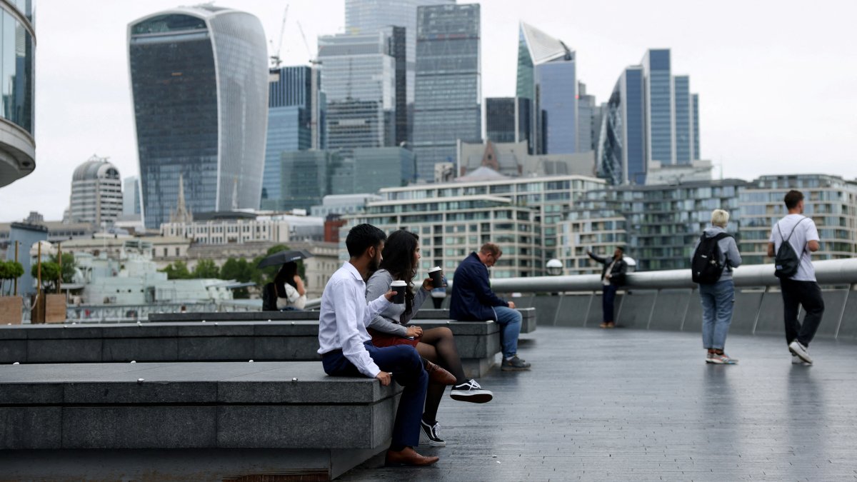 People drink takeaway coffee in view of the City of London skyline in London, U.K., July 25, 2024. (Reuters Photo)