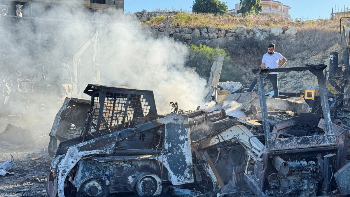 A man stands at a damaged site that sold heavy machinery, as white smoke rises, in the aftermath of Israeli airstrikes, in the southern village of Msayleh, Lebanon, Oct.11, 2025. (Reuters Photo)