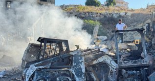 A man stands at a damaged site that sold heavy machinery, as white smoke rises, in the aftermath of Israeli airstrikes, in the southern village of Msayleh, Lebanon, Oct.11, 2025. (Reuters Photo)
