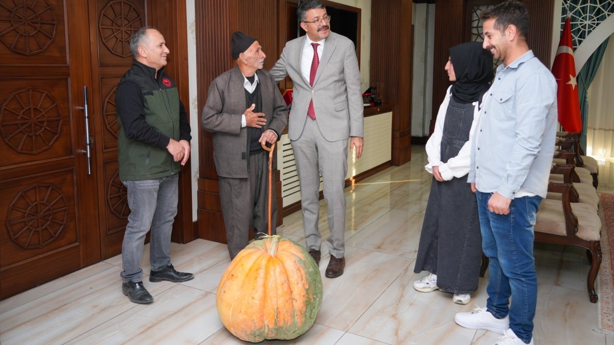 Hacı Osman Salim (2nd L) and his daughter Kübra Salim (2nd R) are welcomed by Governor Ali Çelik as they present the record-breaking pumpkin they grew in Hakkari, southeastern Türkiye, Oct. 17, 2025. (IHA Photo)