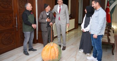 Hacı Osman Salim (2nd L) and his daughter Kübra Salim (2nd R) are welcomed by Governor Ali Çelik as they present the record-breaking pumpkin they grew in Hakkari, southeastern Türkiye, Oct. 17, 2025. (IHA Photo)