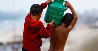 Displaced Palestinian children carry a water container amid a cease-fire, central Gaza, Palestine, Oct. 12, 2025. (Reuters Photo)