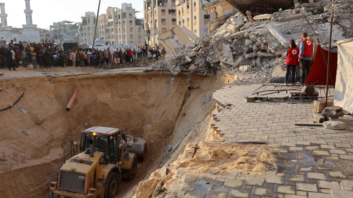 People and members of the International Committee of the Red Cross (ICRC) watch, as Palestinians use excavators to dig deep into the ground, reportedly searching for bodies in Khan Yunis in the southern Gaza Strip, Oct. 17, 2025. (AFP Photo)