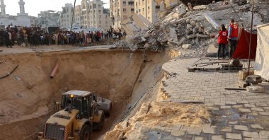 People and members of the International Committee of the Red Cross (ICRC) watch, as Palestinians use excavators to dig deep into the ground, reportedly searching for bodies in Khan Yunis in the southern Gaza Strip, Oct. 17, 2025. (AFP Photo)