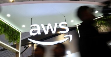 People walk past the logo of Amazon Web Services (AWS) at its exhibitor stall at the India Mobile Congress 2025 at Yashobhoomi, a convention and expo center, New Delhi, India, Oct. 8, 2025. (Reuters Photo)