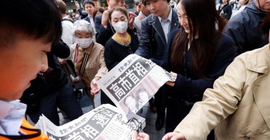 People receive extra editions of a newspaper reporting that the leader of Japan&#039;s ruling Liberal Democratic Party (LDP), Sanae Takaichi, has become Japan&#039;s new prime minister, in Tokyo, Japan, Oct. 21, 2025. (Reuters Photo)