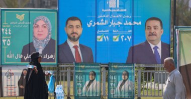 A woman walks past electoral billboards in central Baghdad on Oct. 19, 2025. (Photo AFP)