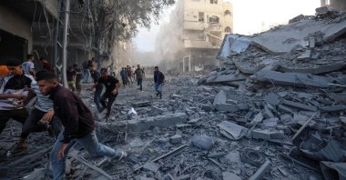 People run for cover following an Israeli strike that targeted a building in the Bureij camp in the central Gaza Strip, Palestine, Oct. 19, 2025. (AFP Photo)