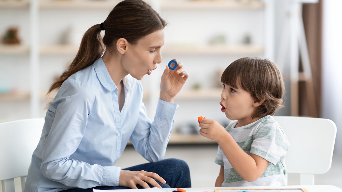 A speech therapist helps a child overcome speech difficulties while the child learns the letter O. (Shutterstock Photo)