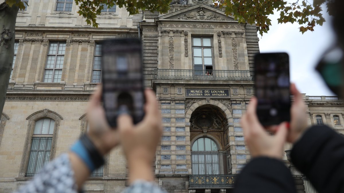 Tourists take photos of the window used by thieves to break into the Louvre Museum in Paris, France, Oct. 20, 2025. (AA Photo)