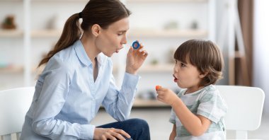 A speech therapist helps a child overcome speech difficulties while the child learns the letter O. (Shutterstock Photo)