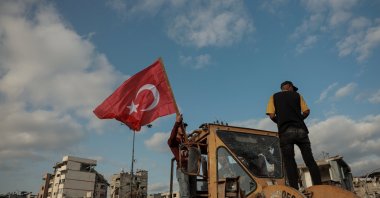 A man places a Turkish flag on a bulldozer sent by a Turkish charity to clear the rubble, Gaza Strip, Palestine, Oct. 18, 2025. (AA Photo)