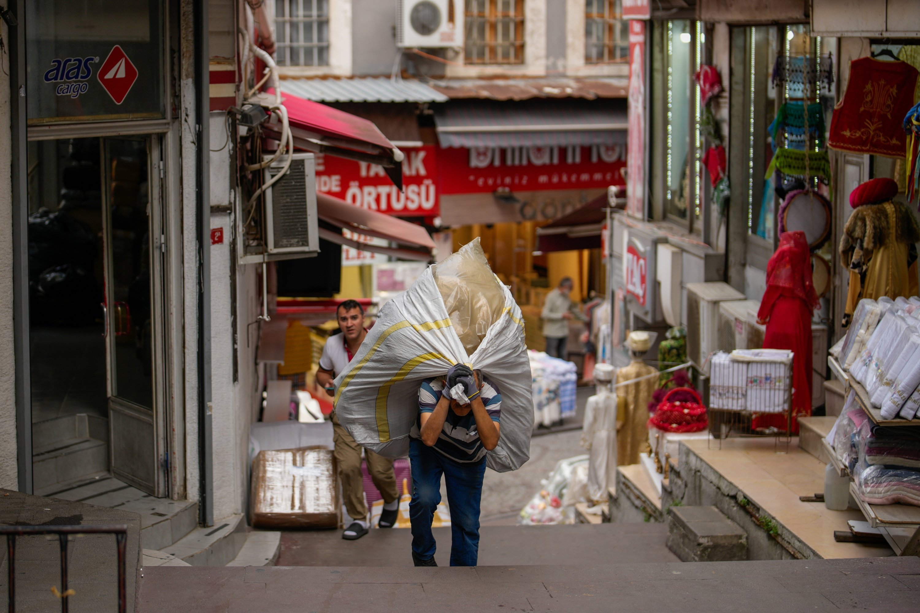 A porter carries a load on his back up the stairs in the Eminonu commercial area, Istanbul, Türkiye, Sept. 24, 2025. (AP Photo)