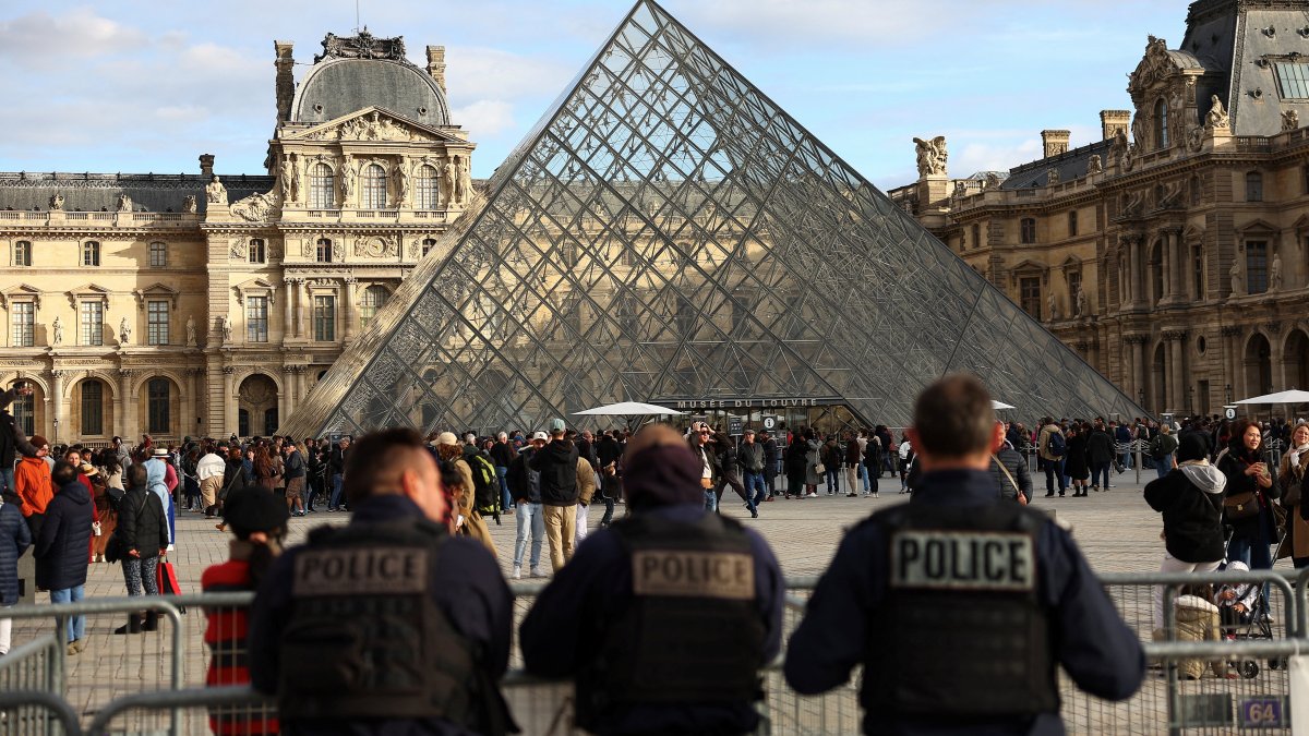 Police officers stand guard near the Louvre Pyramid, after French police arrested suspects in the Louvre heist case, at the Louvre Museum in Paris, France, Oct. 26, 2025. (Reuters Photo)