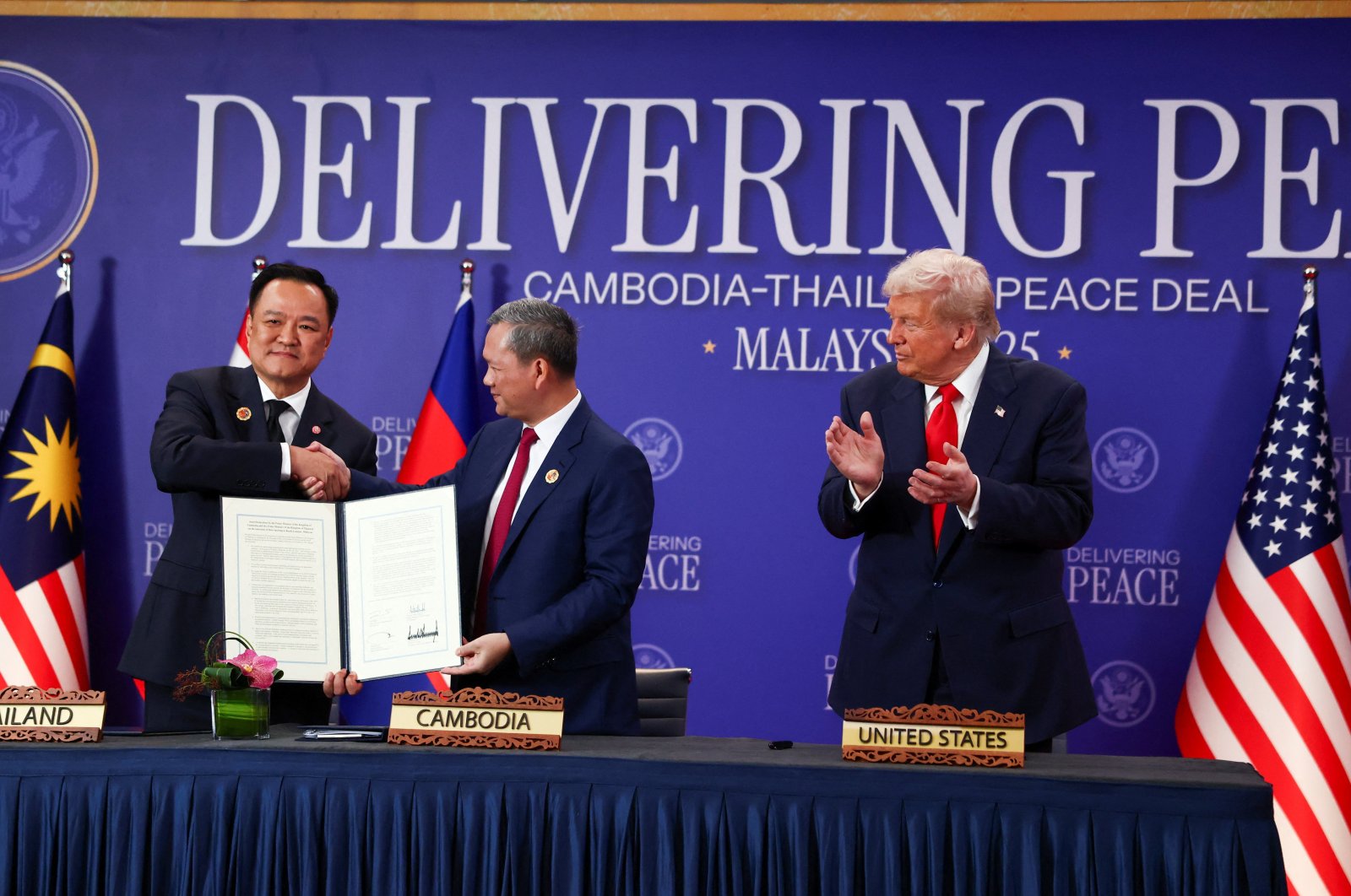Thailand&#039;s Prime Minister Anutin Charnvirakul (L) and Cambodia’s Prime Minister Hun Manet shake hands and hold up a cease-fire document, while U.S. President Donald Trump applauds, in Kuala Lumpur, Malaysia, Oct. 26, 2025. (Reuters Photo)