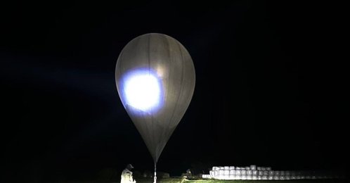 In this undated photo released by the State Border Guard Service, an officer inspects a balloon used to carry cigarettes into Lithuania, because Belarussian smugglers often use them to ferry the contraband into the European Union (AP Photo)