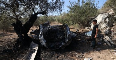 A youth inspects a scorched vehicle at the site where three Palestinians were killed by Israeli soldiers at Kafr Qoud, near Jenin, West Bank, Oct. 28, 2025. (EPA Photo)