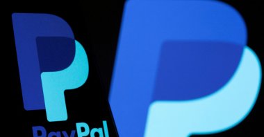 The PayPal logo is seen on a smartphone in front of the same logo displayed in this illustration taken Sept. 8, 2021. (Reuters Photo)