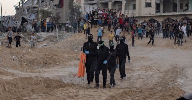  Palestinians watch as members of the Al-Qassam Brigades, the military wing of Hamas, retrieve the body of an Israeli hostage from a tunnel in the Hamad City area of Khan Younis, southern Gaza, Oct. 28, 2025. (EPA Photo)