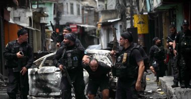 Police officers escort a suspect arrested during the Operacao Contencao (Operation Containment) out of the Vila Cruzeiro favela, in the Penha complex, in Rio de Janeiro, Brazil, Oct. 28, 2025. (AFP Photo)