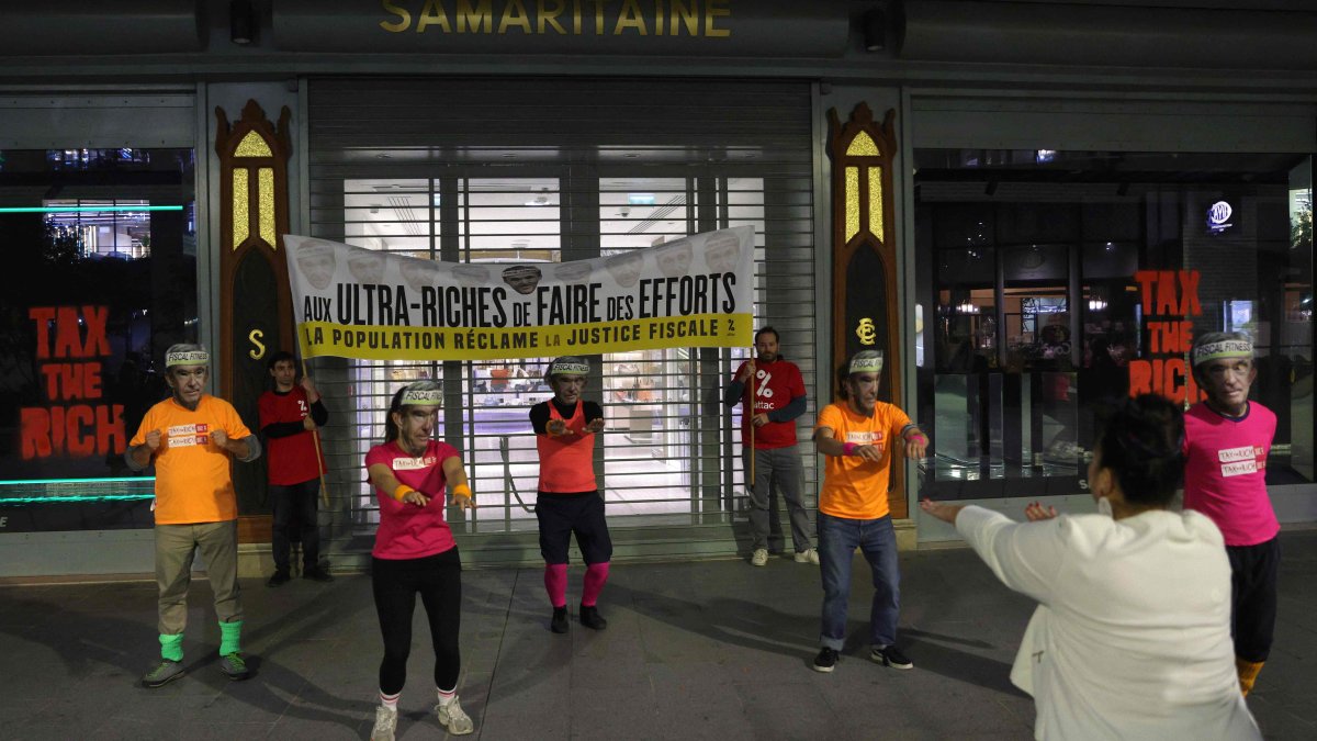 Members of Citizens' Action (Attac), dressed in sports outfits and masks, take part in a "fiscal fitness" session as they stand in front of a banner banner reading "The ultra-rich should make an Effort," as they pretend to take part in an early morning excercise session during a symbolic protest, outside of the La Samaritaine department store, owned by the luxury goods conglomerate LVMH, central Paris, France, Oct. 1, 2025. (AFP Photo)