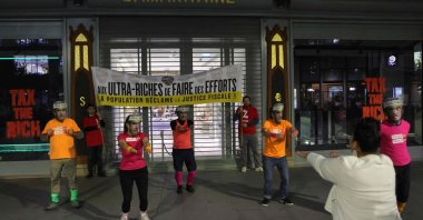 Members of Citizens&#039; Action (Attac), dressed in sports outfits and masks, take part in a &quot;fiscal fitness&quot; session as they stand in front of a banner banner reading &quot;The ultra-rich should make an Effort,&quot; as they pretend to take part in an early morning excercise session during a symbolic protest, outside of the La Samaritaine department store, owned by the luxury goods conglomerate LVMH, central Paris, France, Oct. 1, 2025. (AFP Photo)