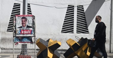 A man walks past a poster of Venezuelan President Nicolas Maduro and an anti-tank barricade in Caracas, Oct. 28, 2025. (AFP Photo)