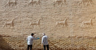 Workers clean salt deposits from a wall decorated with animal reliefs at Babylon, a UNESCO World Heritage site, Babylon, Iraq, Oct. 22, 2025. (Reuters Photo)