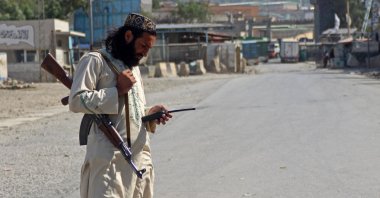 A Taliban security personnel uses a wireless device as he stands near the closed Torkham border crossing between Afghanistan and Pakistan in Nangarhar province on October 21, 2025. After a week of violence, residents on the frontier between Afghanistan and Pakistan are hoping a new ceasefire deal will end the clashes and revive crucial cross-border trade. (Photo by AFP)
