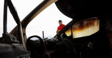 A Palestinian man stands near a car burned by Israeli settlers in the Palestinian village of Atara, near Ramallah, in the Israeli-Occupied West Bank, Oct. 29, 2025. (Reuters Photo)