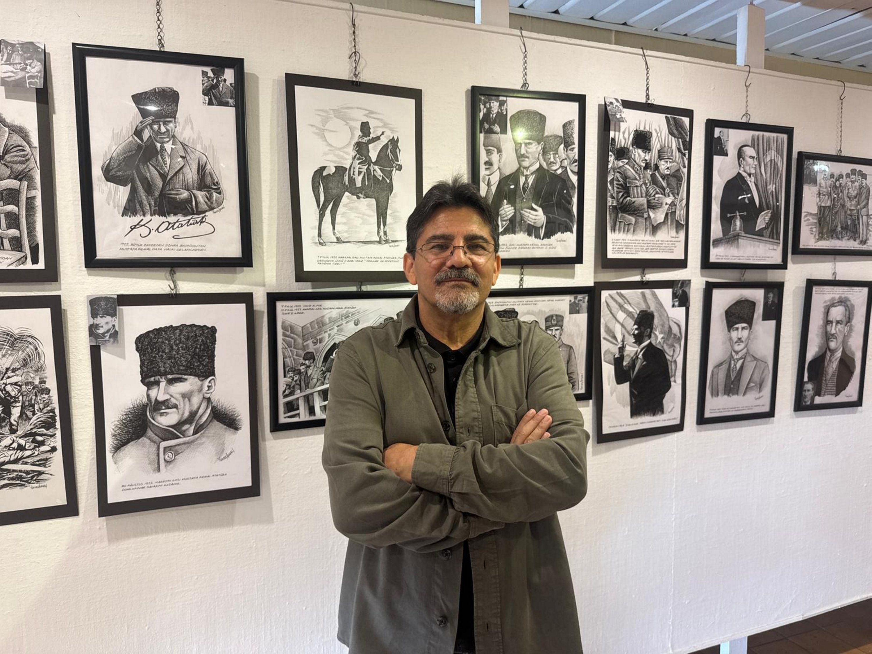 Artist Yüksel Akman poses with his charcoal drawings on display at the TGC Press Media Museum, Istanbul, Türkiye, Oct. 30, 2025. (AA Photo)