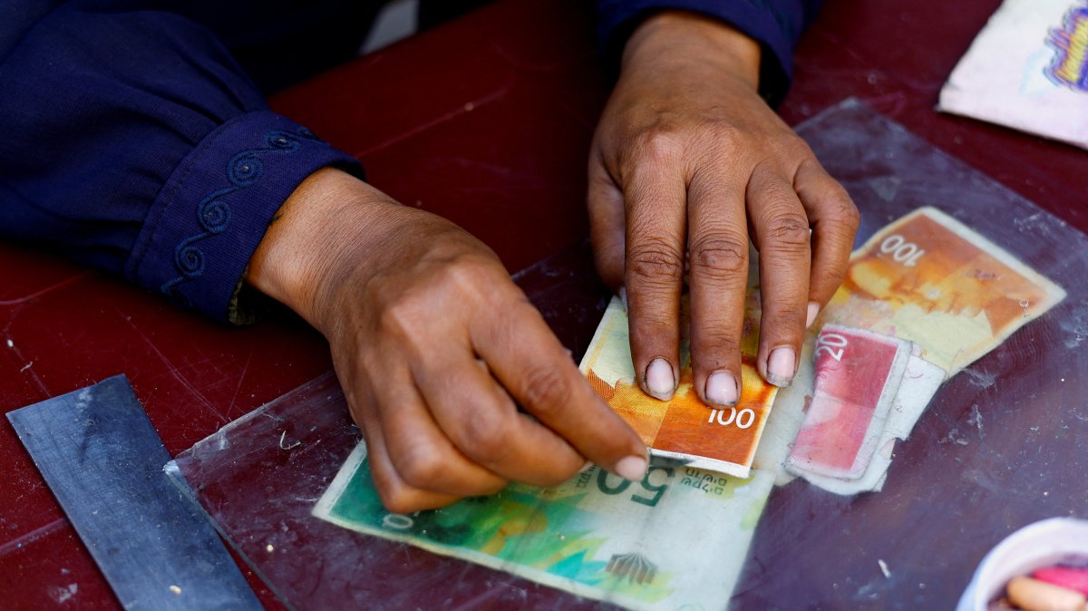 Palestinian woman Manal al-Saidi repairs damaged banknotes on the side of a street, amid a cash crisis, in Nuseirat, Gaza Strip, Palestine, Oct. 27, 2025. (Reuters Photo)