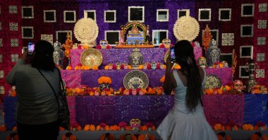 Visitors photograph a Day of the Dead altar adorned with sugar skulls known as “calaveritas” or little skulls, at the Casa de Mujeres Artesanas Indígenas in downtown Mexico City, Friday, Oct. 31, 2025. (AP Photo)