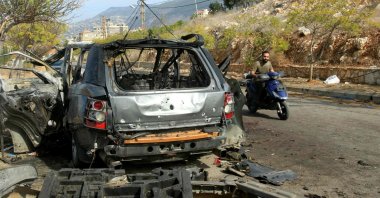 A man rides his scooter past the wreckage of a vehicle, a day after an Israeli airstrike killed its occupants, in Kfar Roummane, southern Lebanon, Nov. 2, 2025. (AFP Photo)