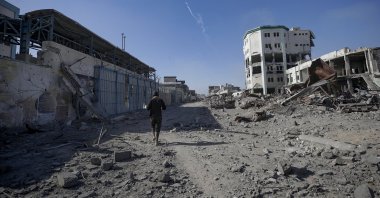 A Palestinian man walks near UNRWA headquarters (L) along a devastated street in Gaza, Palestine, Oct. 10, 2025. (EPA Photo)