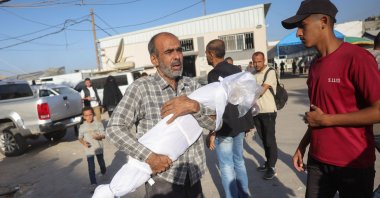 A Palestinian man carries the draped body of a child killed in Israeli strikes the previous day on the central Gaza Strip, outside the Shuhada al-Aqsa hospital ahead of a burial ceremony for the victims in Deir al-Balah, the Gaza Strip, Oct. 20, 2025. (AFP Photo)