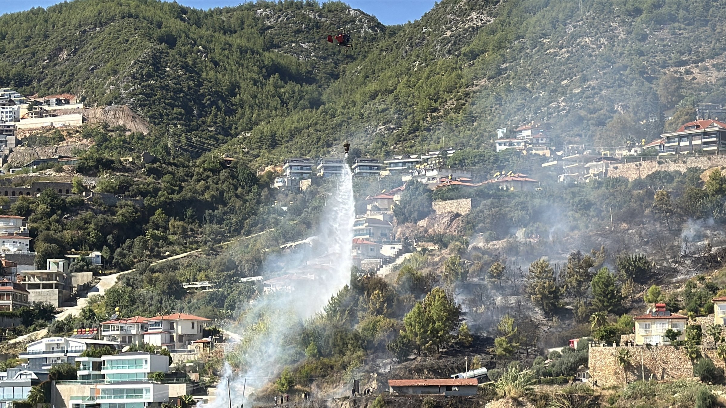 Firefighters extinguish a wildfire near homes before it spreads to them, Alanya, Antalya, Türkiye, Oct. 12, 2025. (AA Photo)