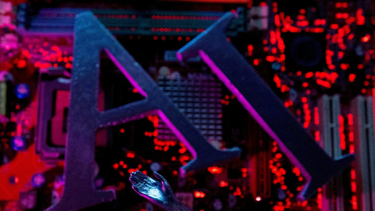 The letters AI (Artificial Intelligence) and a robot hand are placed on a computer motherboard in this illustration, June 23, 2023. (Reuters File Photo)