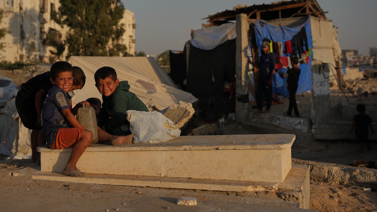 Palestinian children sit on a grave near makeshift tents for displaced people that were set up in a cemetery in Khan Younis, in the southern Gaza Strip, Palestine, Oct. 31, 2025. (AP Photo)