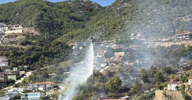 Firefighters extinguish a wildfire near homes before it spreads to them, Alanya, Antalya, Türkiye, Oct. 12, 2025. (AA Photo)