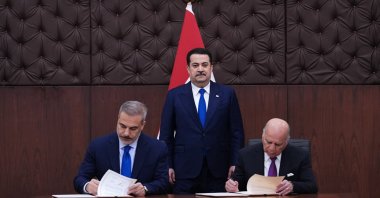 Foreign Ministers Hakan Fidan (L) and Fuad Hussein of Iraq (R) sign the document as Iraqi Prime Minister Mohammed S. Al Sudani watches, Baghdad, Türkiye, Nov. 2, 2025. (AA Photo)