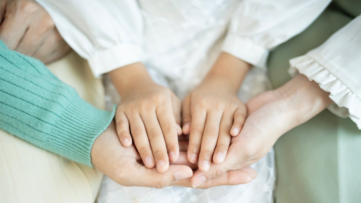 A close-up shows a family holding hands, symbolizing unity and care. (Shutterstock Photo) 