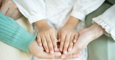 A close-up shows a family holding hands, symbolizing unity and care. (Shutterstock Photo) 