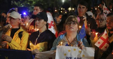 Demonstrators with Georgian and EU flags hold candles standing in front of the Kashveti Church of St. George during an opposition protest against &quot;the Russian law&quot; in the center of Tbilisi, Georgia, May 3, 2024. (AP File Photo)